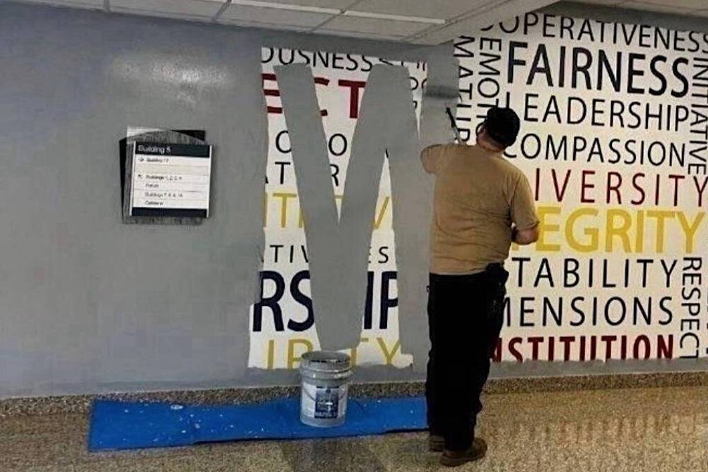 A worker paints over a wall mural featuring words such as fairness, leadership, compassion, diversity and integrity at the FBI Academy at Quantico on Wednesday. (Anonymous photo provided to The New York Times)