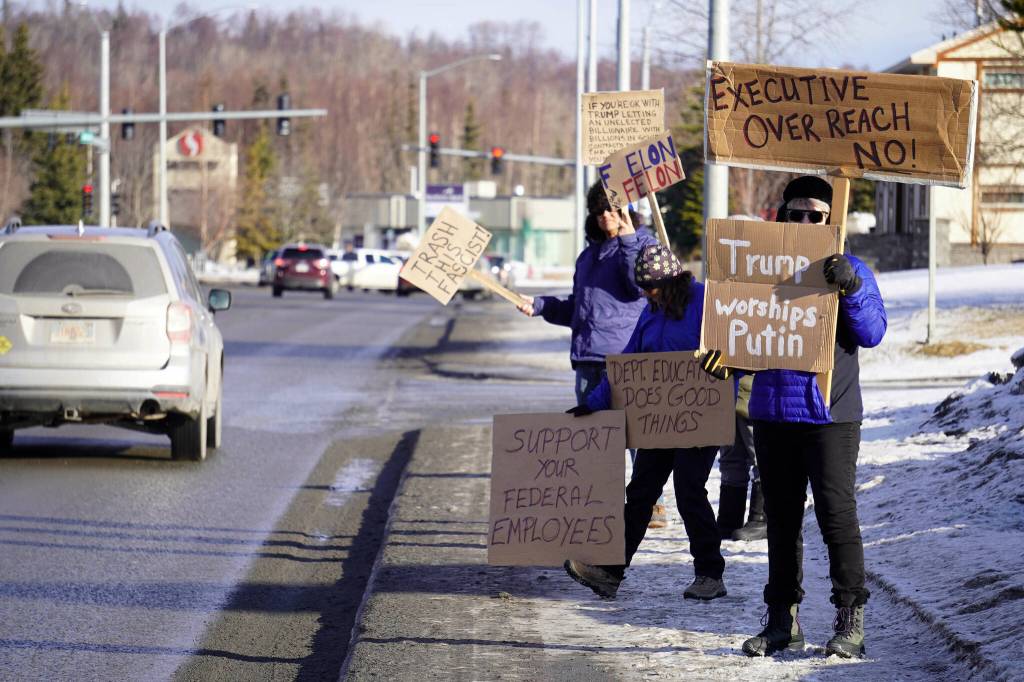 Protesters stand with signs in opposition to executive overreach, President Donald Trump and Elon Musk stand along the Sterling Highway in Soldotna, Alaska, on Monday, Feb. 17, 2025. (Jake Dye/Peninsula Clarion)