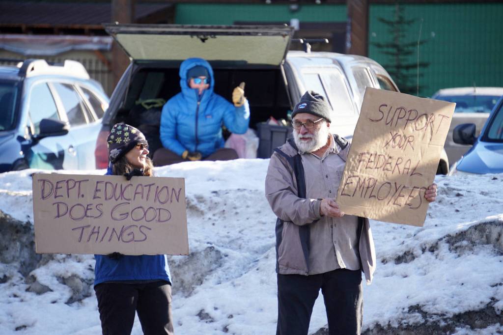 Protesters stand with signs in support of federal employees, federal lands and the U.S. Constitution stand along the Sterling Highway in Soldotna, Alaska, on Monday, Feb. 17, 2025. (Jake Dye/Peninsula Clarion)