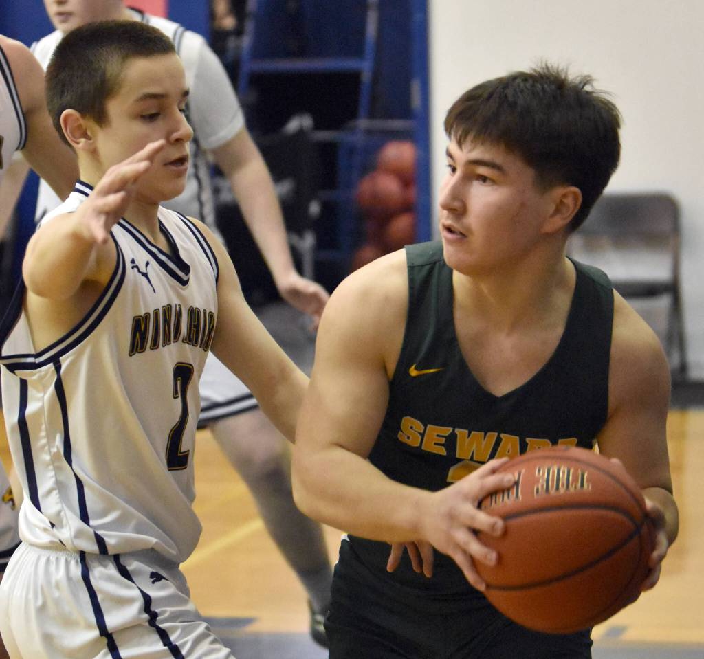 Sewards Noah Price protects the ball from Ninilchiks Eric Rader on Friday, February 21, 2025, at Ninilchik School in Ninilchik, Alaska. (Photo by Jeff Helminiak/Peninsula Clarion)