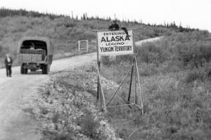 As his wife Bernice looks on, 43-year-old Clarence Hiram Poopdeck Platt poses atop a road sign welcoming him to Alaska. This 1947 photograph from the Huebsch Family Collection memorializes Platts first trip to Alaska, which became his home for the next 53 years.