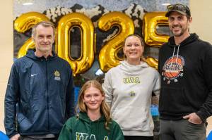 Homer senior Gracie Miotke (seated) committed to run track and field at the University of Alaska Anchorage on Wednesday, March 5, 2025, at Homer High School in Homer, Alaska. Behind Miotke are Homer head coach Bob Ostrom, mother, Amanda Miotke, and father, Dan Miotke. (Photo provided)