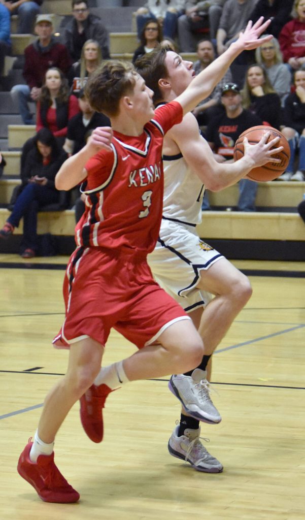 Homers Justus Grimes drives on Kenai Centrals Carter Felchle on Saturday, March 8, 2025, at the Peninsula Conference tournament at Nikiski Middle-High School in Nikiski, Alaska. (Photo by Jeff Helminiak/Peninsula Clarion)