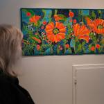 Attendees admire Neon Poppies by Chelline Larsen during the opening reception for Infusion at the Kenai Art Center in Kenai, Alaska, on Friday, March 7, 2025. (Jake Dye/Peninsula Clarion)