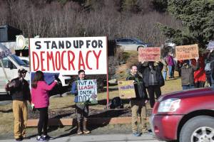 Community members hold up protest signs during the Stand for Democracy Rally on International Womens Day, March 8, 2025, at WKFL Park in Homer, Alaska. (Chloe Pleznac/Homer News)