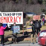 Community members hold up protest signs during the Stand for Democracy Rally on International Womens Day, March 8, 2025, at WKFL Park in Homer, Alaska. (Chloe Pleznac/Homer News)