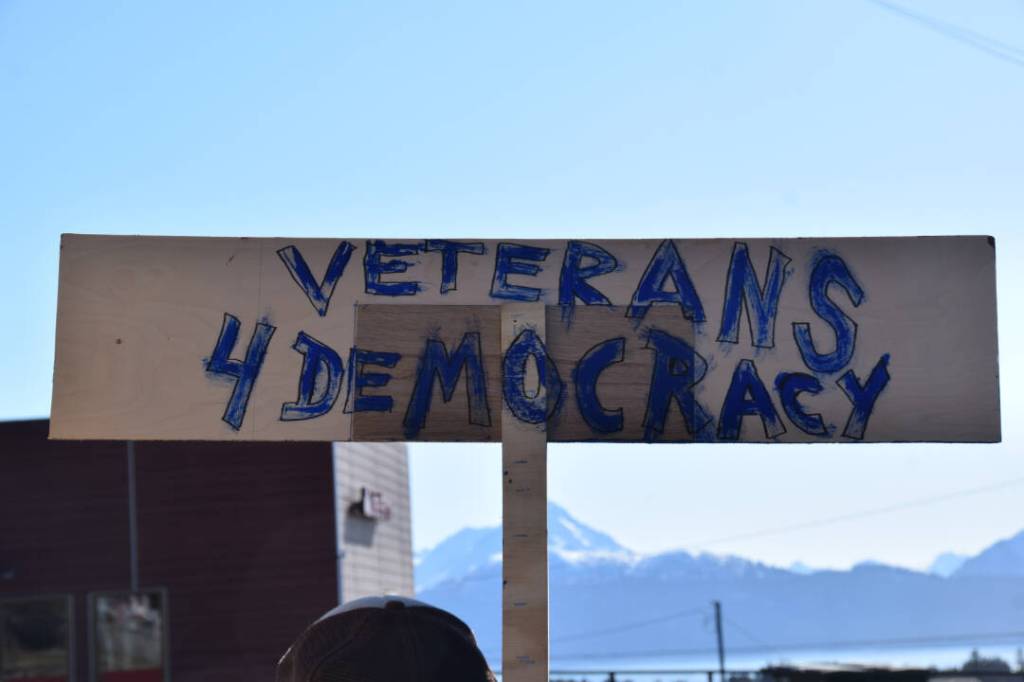 A community member holds up a protest sign at the Stand for Democracy Rally on International Womens Day, March 8, 2025 at WKFL Park in Homer, Alaska. (Chloe Pleznac/Homer News)