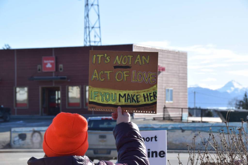 A community member holds up a protest sign during the Stand for Democracy Rally on International Womens Day, March 8, 2025, at WKFL Park in Homer, Alaska. (Chloe Pleznac/Homer News)