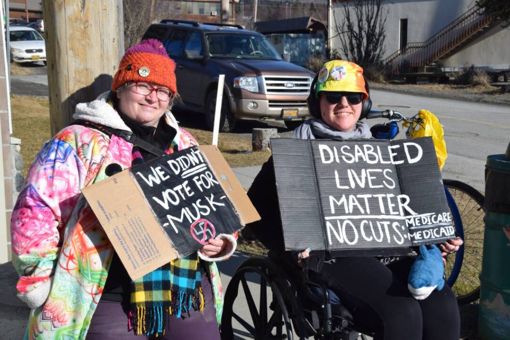 Community members hold up protest signs during the Stand for Democracy Rally on International Womens Day, March 8, 2025, at WKFL Park in Homer, Alaska. (Chloe Pleznac/Homer News)