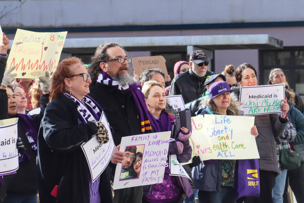 Protestors gather at the Alaska State Capitol on Wednesday, March 12, 2025. Jamie Liston holds a sign that says family is everything. (Jasz Garrett / Juneau Empire)