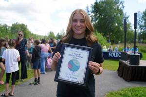 Isla Crouse stands with her award for winning the City of Soldotnas I Voted Sticker Design Contest at the Soldotna Progress Days Block Party in Parker Park in Soldotna, Alaska, on Saturday, July 27, 2024. (Jake Dye/Peninsula Clarion)