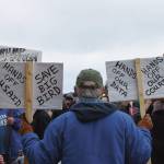 A protester in Homer holds up signs during the nationwide Hands Off! protest on Saturday, April 5 at WKFL Park in Homer, Alaska. (Chloe Pleznac/Homer News)