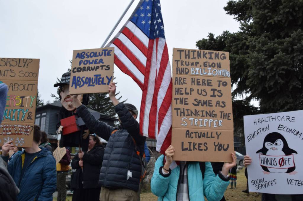 Protesters in Homer hold up signs during the nationwide Hands Off! protest on Saturday, April 5 at WKFL Park in Homer, Alaska. (Chloe Pleznac/Homer News)