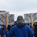 A protester in Homer holds up signs during the nationwide Hands Off! protest on Saturday, April 5 at WKFL Park in Homer, Alaska. (Chloe Pleznac/Homer News)