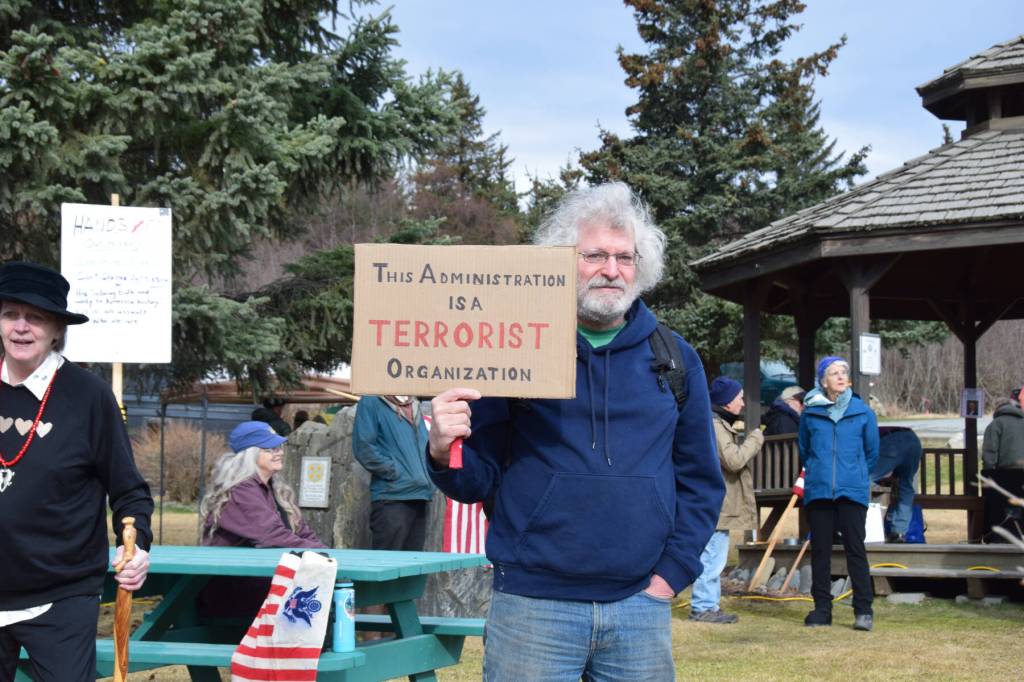 A protester holds up a sign during the nationwide Hands Off! protest on Saturday, April 5 at WKFL Park in Homer, Alaska. (Chloe Pleznac/Homer News)