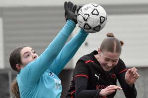 Soldotna goalie Ryan Queen notches a save in front of Kenai Central's Christine Goering on Tuesday, April 15, 2025, at Ed Hollier Field at Kenai Central High School in Kenai, Alaska. (Photo by Jeff Helminiak/Peninsula Clarion)
