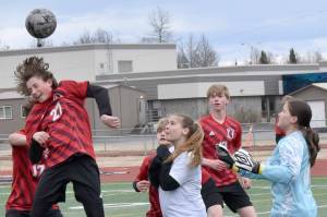 Kenai Central's Diego Huerta heads the ball in front of Nikiski defender Jayden Anderson and goalie Emily Brannen on Tuesday, April 29, 2025, at Ed Hollier Field at Kenai Central High School in Kenai, Alaska. (Photo by Jeff Helminiak/Peninsula Clarion)
