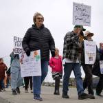 People carry signs and stand as part of a May Day protest alongside the Sterling Highway in Soldotna, Alaska, on Thursday, May 1, 2025. (Jake Dye/Peninsula Clarion)