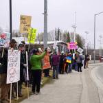 People carry signs and stand as part of a May Day protest alongside the Sterling Highway in Soldotna, Alaska, on Thursday, May 1, 2025. (Jake Dye/Peninsula Clarion)