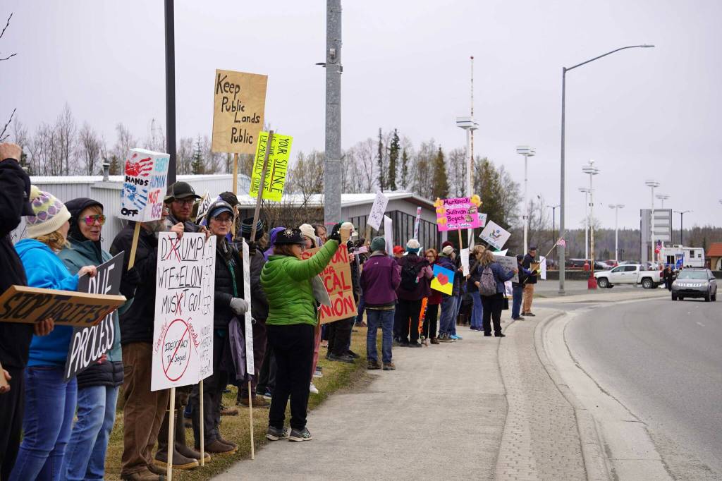 People carry signs and stand as part of a May Day protest alongside the Sterling Highway in Soldotna, Alaska, on Thursday, May 1, 2025. (Jake Dye/Peninsula Clarion)