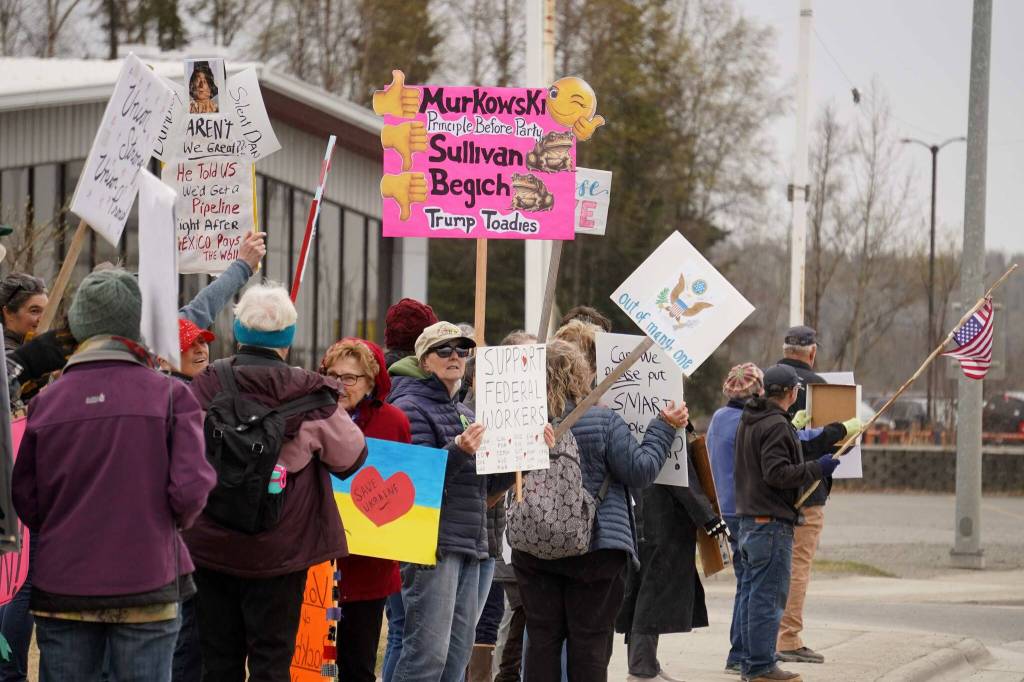 People carry signs and stand as part of a May Day protest alongside the Sterling Highway in Soldotna, Alaska, on Thursday, May 1, 2025. (Jake Dye/Peninsula Clarion)