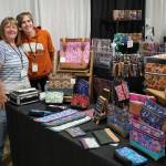 Kathy Waterbury and Tasha Dawson stand at their booths for Fireweed Stitches and Bear Mountain Designs during the 38th Annual Kenai Peninsula Sport, Rec & Trade Show at the Soldotna Regional Sports Complex in Soldotna, Alaska, on Friday, May 2, 2025. (Jake Dye/Peninsula Clarion)