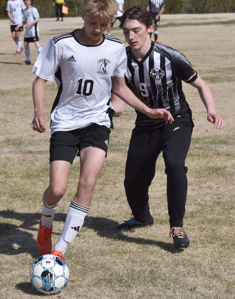 Kenai Centrals Lucas Swanson shields the ball from Nikiskis Shane Hall on Friday, May 16, 2025, at Nikiski Middle-High School in Nikiski, Alaska. (Photo by Jeff Helminiak/Peninsula Clarion)