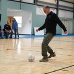 Kenai Peninsula Borough Mayor Peter Micciche kicks a dedicating goal during a ribbon-cutting event for the Boys and Girls Clubs of the Kenai Peninsulas Royce and Melba Roberts Campus in Kenai, Alaska, on Saturday, May 17, 2025. (Jake Dye/Peninsula Clarion)