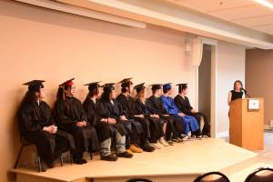 Homer Flex counselor Sue Rennolds (right) speaks to the graduating class of 2025 during the commencement ceremony held Wednesday, May 21, 2025, at Lands End Resort in Homer, Alaska. (Delcenia Cosman/Homer News)