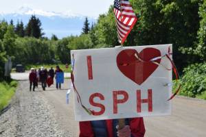 A woman stands with her sign held up during a rally in support of Medicaid and South Peninsula Hospital on Wednesday, June 18, 2025 in Homer, Alaska. (Chloe Pleznac/Homer News)