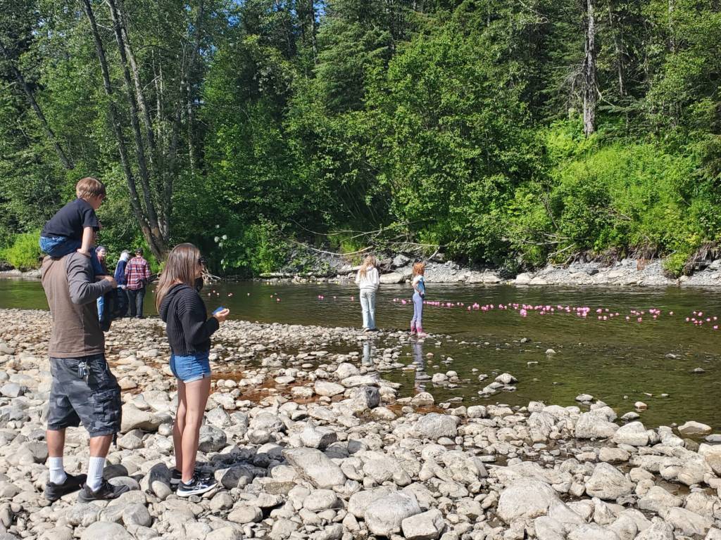 Community members watch ducks float by on the Anchor River during the annual Anchor River Duck Races on Saturday, July 5, 2025, in Anchor Point, Alaska. (Delcenia Cosman/Homer News)