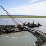 Armor rock from Sand Point is offloaded from a barge in the Kenai River in Kenai, Alaska, part of ongoing construction efforts for the Kenai River Bluff Stabilization Project on Wednesday, July 23, 2025. (Jake Dye/Peninsula Clarion)