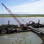 Armor rock from Sand Point is offloaded from a barge in the Kenai River in Kenai, Alaska, part of ongoing construction efforts for the Kenai River Bluff Stabilization Project on Wednesday, July 23, 2025. (Jake Dye/Peninsula Clarion)
