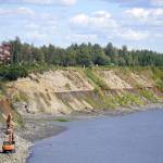 Armor rock from Sand Point is offloaded from a barge in the Kenai River in Kenai, Alaska, part of ongoing construction efforts for the Kenai River Bluff Stabilization Project on Wednesday, July 23, 2025. (Jake Dye/Peninsula Clarion)