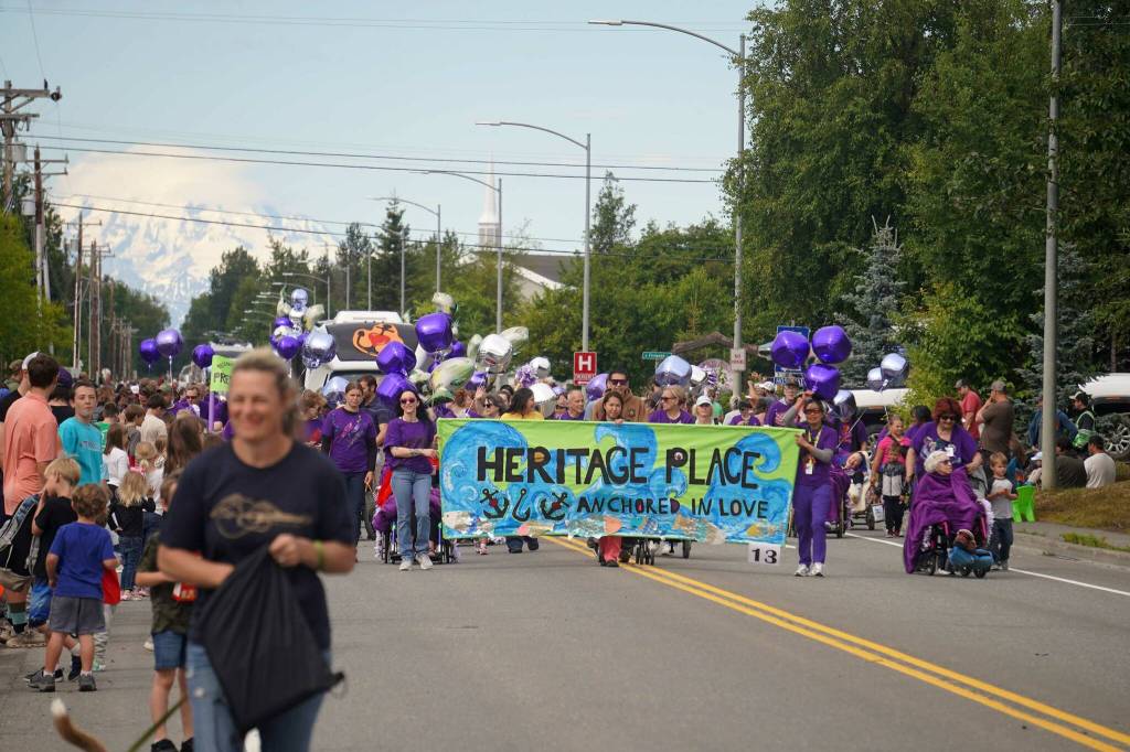 A large contingent of people representing Heritage Place flood Marydale Avenue with the color purple during the 68th Annual Soldotna Progress Days Parade in Soldotna, Alaska, on Saturday, July 26, 2025. (Jake Dye/Peninsula Clarion)