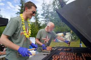 Soldotna City Council member Jordan Chilson and Soldotna Mayor Paul Whitney grill hot dogs at the Progress Days Block Party at Parker Park in Soldotna, Alaska, on Saturday, July 26, 2025. (Jake Dye/Peninsula Clarion)