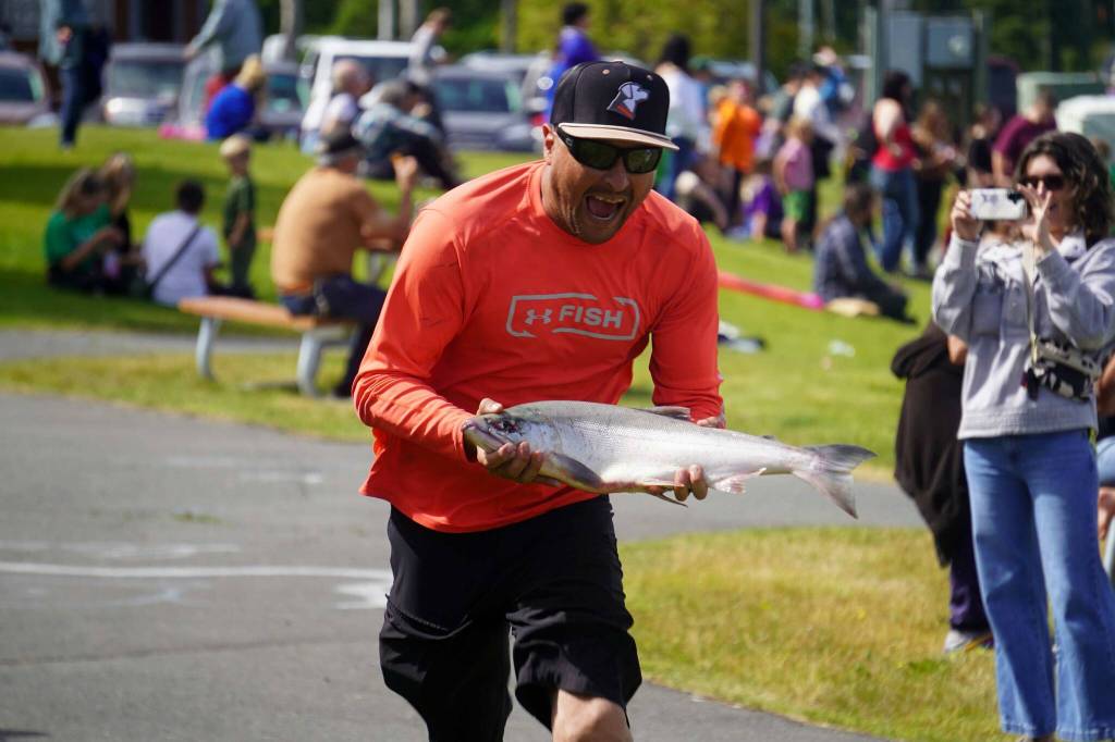 Contestants carry real sockeye salmon in the sockeye sprint, one of the contests at the Progress Days Block Party at Parker Park in Soldotna, Alaska, on Saturday, July 26, 2025. (Jake Dye/Peninsula Clarion)