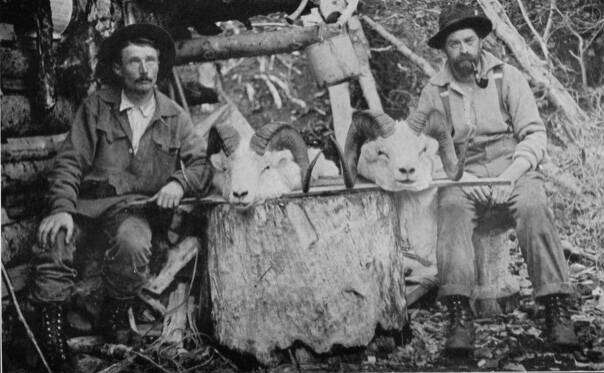 Posing in front of Steve Melchiors cabin on the Killey River in 1912 are (left) packer/cook Ferdinand Fritz Posth and hunting guide William Wild Bill Dewitt, with two trophy Dall sheep heads. (Photo from E. Marshall Sculls 1914 hunting memoir, Hunting in the Arctic and Alaska)