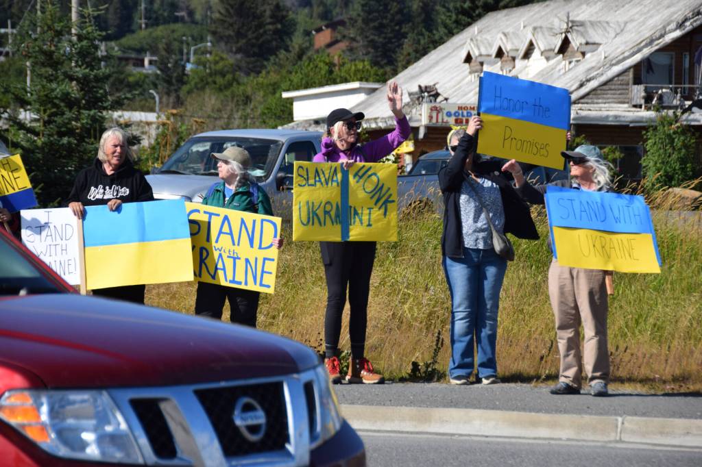 Cars pass through the intersection of Lake Street and the Sterling Highway as protesters hold up signs expressing support for Ukraine on Friday, Aug. 15, 2025, in Homer, Alaska. (Delcenia Cosman/Homer News)