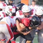 Kenai juniors Blake Morris (52) and Jackson Taliesin (66) lead a group of Kardinals as they bring down Houston’s Mason Green during a 31-22 win over Houston on Friday, Sept. 5, at Houston High School in Houston, Alaska. (Photo by Jeremiah Bartz/Frontiersman)