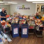 Organizers stand alongside carts filled with food collected during the Freedom from Hunger community food drive at the Kenai Peninsula Food Bank near Soldotna, Alaska, on Friday, Sept. 19, 2025. (Jake Dye/Peninsula Clarion)