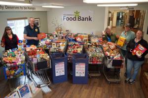 Organizers stand alongside carts filled with food collected during the Freedom from Hunger community food drive at the Kenai Peninsula Food Bank near Soldotna, Alaska, on Friday, Sept. 19, 2025. (Jake Dye/Peninsula Clarion)