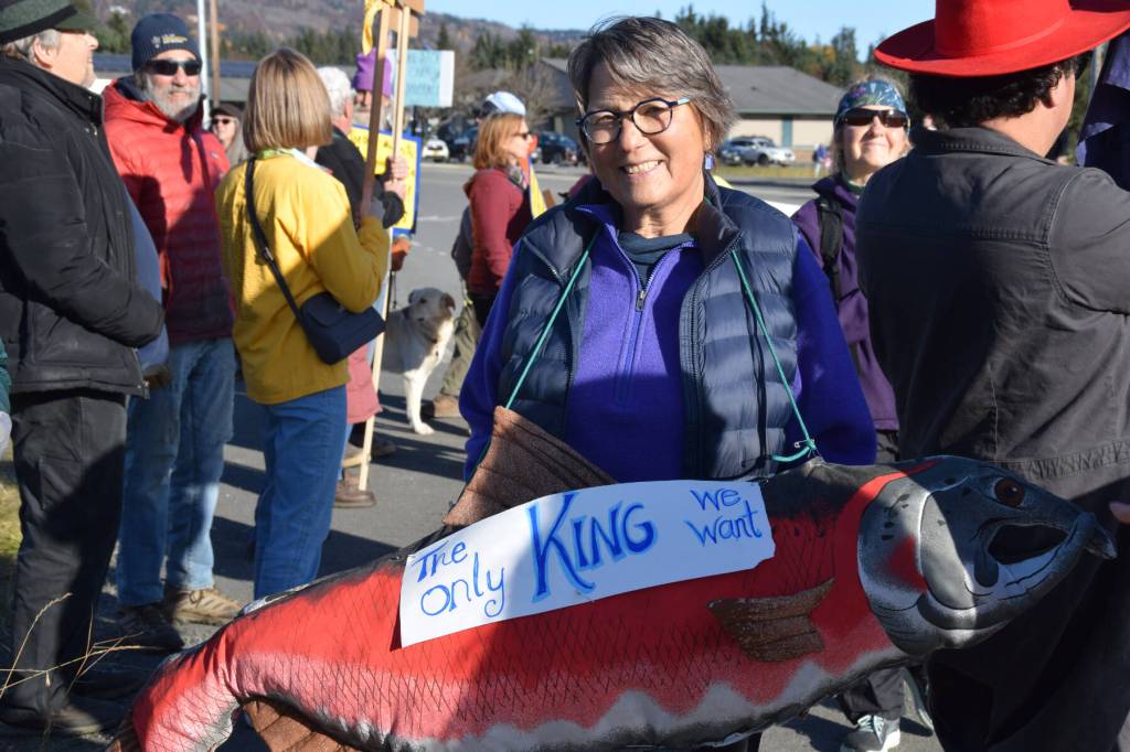 A protester carries a stuffed king salmon with a sign that reads The only King we want during the No Kings protest on Saturday, Oct. 18, 2025, in Homer, Alaska. (Delcenia Cosman/Homer News)