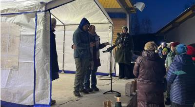 Alexander Sanchez-Ramos (center left) stands with Karen Martin Tichenor (center right) during a vigil held Sunday, March 1, 2026, at Soldotna Creek Park in Soldotna, Alaska. The vigil was in support of Sanchez-Ramos wife, Sonia Espinoza Arriaga, and her three children who were deported by federal immigration officers in February. Sanchez-Ramos is seen holding his phone in this photo; he was connected to Arriaga on FaceTime so she could witness the vigil as well. Photo courtesy Meredith Harber