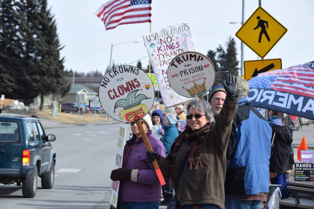 Protesters line up along Pioneer Avenue and hold up signs that read, No Crowns for Clowns and Trump for Prison, Make America Safe Again, during the third nationally-organized No Kings protest on Saturday, March 28, 2026, in Homer, Alaska. (Delcenia Cosman/Homer News)