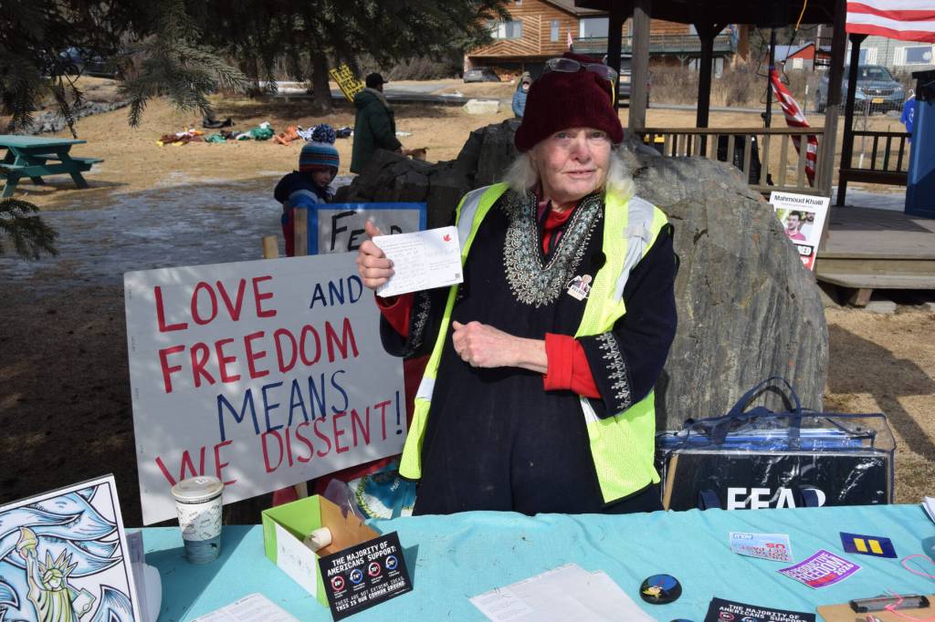 Kate Finn with Homer Women of Action holds up postcards that protest attendees could send to their legislative constituents during the No Kings protest on Saturday, March 28, 2026, in Homer, Alaska. (Delcenia Cosman/Homer News)