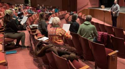 Kyle Schneider instructs community members during a February 2023 community chorus at the Mariner Theatre. (Photo by Christina Whiting/Homer News file)