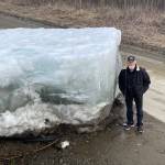 (Eagle resident Steve Hamilton stands next to a block of Yukon River ice that the river lifted onto a road there on May 12, 2023. (Photo by Ned Rozell)