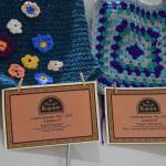 Memorial certificates are displayed with framing squares created by local fiber arts on a memory wall, part of the Mozart "Requiem" performance on Friday, May 1, 2026, in Homer, Alaska. (Delcenia Cosman/Homer News)