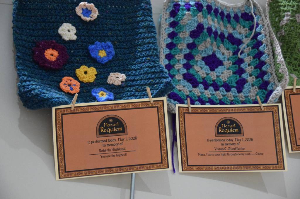 Memorial certificates are displayed with framing squares created by local fiber arts on a memory wall, part of the Mozart "Requiem" performance on Friday, May 1, 2026, in Homer, Alaska. (Delcenia Cosman/Homer News)